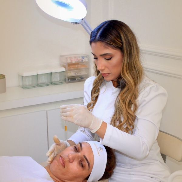 Marcella Porto realizando atendimento estético em paciente durante tratamento facial na MELAMCLINIC